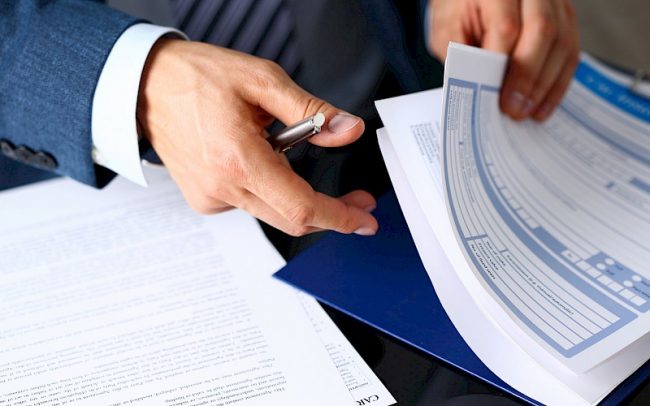 Male arm in suit offer insurance form clipped to pad dieu kien incoterms