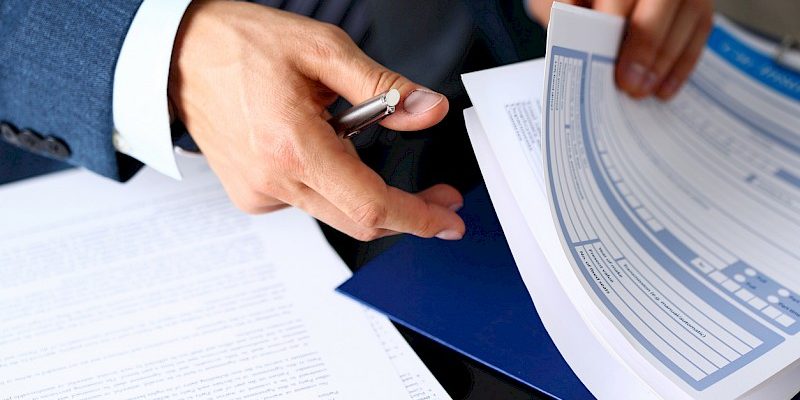 Male arm in suit offer insurance form clipped to pad dieu kien incoterms